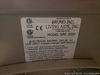 Close-up photo of the manufacturer's label showing information about the model SRE-3000 chair lift by Bruno Ind. Living Aids Inc., with electrical rating and usage notes.