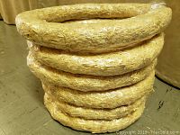 Six straw crafting wreaths stacked and wrapped in plastic.