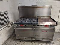 Front view of entire stainless steel Vulcan gas range showing six burners, integrated griddle, control knobs and dual oven doors