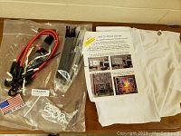 Projector screen materials and accessories including folded white screen fabric, red cables with hooks, zip ties, white plastic hooks or inserts, and an instruction letter.