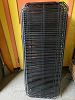 Stack of 14 black metal wire shelves, showing shape and size