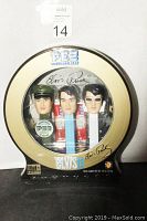 Front view of round display packaging showing three Elvis PEZ dispensers in different eras and accompanying PEZ candy.