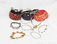 Photo showing a collection of 13 vintage bracelets including three large patterned bangles, two rhinestone 'VOTE' bracelets, a silver-tone link bracelet, a gold-tone charm bracelet, and multiple colorful beaded bracelets.
