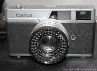 Front view of the vintage Canon 35mm camera showing the Canon logo, lens details, and circular light meter ring.