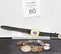 Overall view of the wristwatch with black leather strap and vintage coin bracelet laid out together