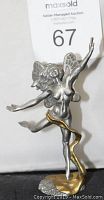 Front view of the pewter dancing fairy figurine with outstretched arm and flowing gold ribbon.