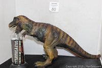 Large T-Rex dinosaur figure in profile showing lifelike skin texture and coloration, standing with open mouth and visible teeth