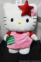 Front view of Hello Kitty plush with star decorations on head and holding green object, showing full height and details.