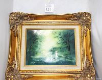 Front view of vintage painting depicting a forest scene with figure in light, set in ornate gold Art Deco frame.