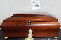 Front view of solid wood jewelry box with polished finish and tassel on the latch.