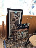 Photo showing three framed wall art/collage photo frames and an ornate metal 4-candle candelabra on the floor against a wall.