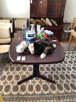 Dining table with items on top and two leaves stored underneath