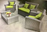 Full view of 4-piece gray resin wicker patio set with green cushions and tempered glass coffee table