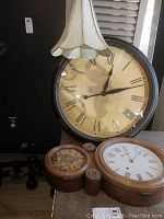 Shows Infinity 24 inch round wall clock, antique wooden clock, smaller clocks, and hanging pendant lamp