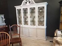 Full view of the white two-piece china cabinet, showing upper glass doors with lattice design and lower solid doors.