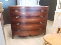 Front view of the wooden dresser with four curved drawers and metal oval handles.