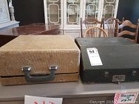 Two typewriter cases side by side on a table. Beige Royal Portable case on left, black Smith Corona case on right.