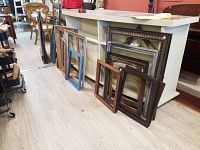Several empty picture frames lined up against low counter, showing different sizes and finishes.