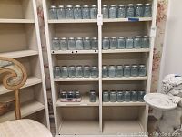 Shelves filled with multiple rows of blue glass mason jars with metal lids.