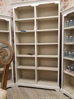 Front view of tall white painted wooden bookshelf showing two columns of shelves