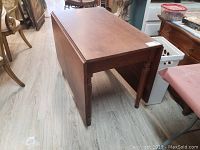 Closed wooden dropleaf table showing top and one side leaf folded down