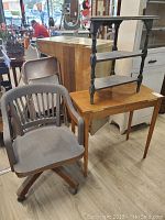 Overall view showing the wooden hall table, wooden side table placed on the hall table, and vintage wooden rolling office chair in front of them.