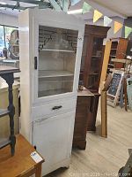 Full front view of white wood and glass curio cabinet with some visible wear and scratches.