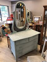 Full front view of painted antique dresser with attached oval mirror showing drawer fronts and decorative painted top.