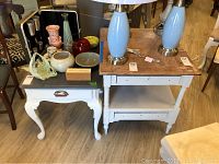 Two wooden side tables displayed together, one with black top and curved white legs, the other with natural wood top and white base with lower shelf.