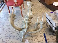 Full view of the six-light chandelier showing the curved arms and the beige over gold finish with decorative carvings.