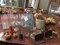 Overall view of the lot showing glass vases, pottery, wooden shoes, wood finials and tulips, metal bookends, and other items on a table indoors.