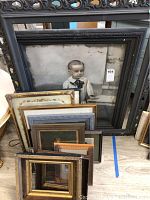 Image showing a stack of multiple frames including a large frame with a vintage portrait of a young child and smaller empty frames of various finishes.