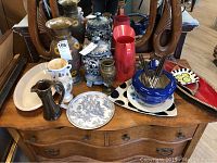 Overview of assortment of metal and ceramic vases, pitchers, and plates on wooden table.