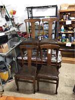 Four oak side chairs with wooden backs and padded seats arranged around a wood coffee table on wheels.