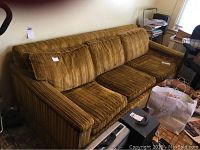 Full view of vintage sleeper sofa in striped brown and gold fabric with multiple cushions on seat and backrest.