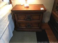 Bedside table front view showing solid hardwood construction and two drawers with ornate metal hardware.