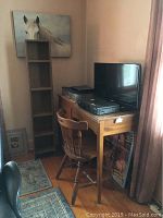 Full view of the tall slim shelf next to the solid wood desk with wooden chair, showing arrangement and size comparison in room