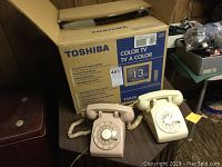 Toshiba 13-inch color CRT TV in original box with two vintage rotary phones placed on table