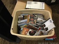 Plastic bin filled with a large quantity of CDs in jewel cases, stacked and loosely arranged.