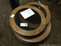 Three round wood framed glass top tables stacked. Top table has swing mechanism and some alignment issues.