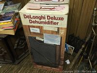 Photo showing the original box of DeLonghi Deluxe Dehumidifier with branding and product image.