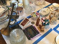 Overall view of the lot showing the trumpet figurine, glass candy dish, porcelain figurines, cup and saucer, and seashell animal figurines on a table.