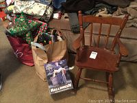Photo with kids wooden rocking chair next to various holiday gift bags and Halloween prop kit box