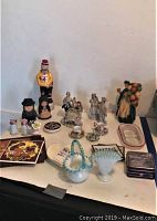 Full display of assorted figurines, bone china, porcelain basket, trivets, and decorative items on table