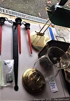 Photo showing the red candles in black wrought iron candle sconce, brass and glass desk lamp base and chimney, partially viewed brass oil lamp lantern.