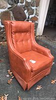 Orange vinyl vintage armchair with tufted backrest and padded arms.