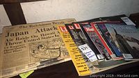 Photo showing a set of vintage newspapers and magazines stacked on a table including The Hutchinson Herald with a prominent headline about Japan attacking Hawaii, and a mix of Life and Time magazines.