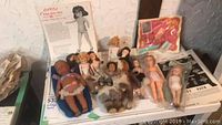 Overview photo showing multiple vintage dolls, including the Richards Carroll doll, Native Alaskan dolls, and other vintage plastic dolls along with papers and accessories.