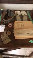 Ammunition belt, slippers, patch, service button bag and stack of books viewed from above on wooden table.