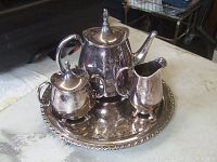 Complete tea service set with teapot, creamer, sugar bowl on round silverplate tray with decorative edge.